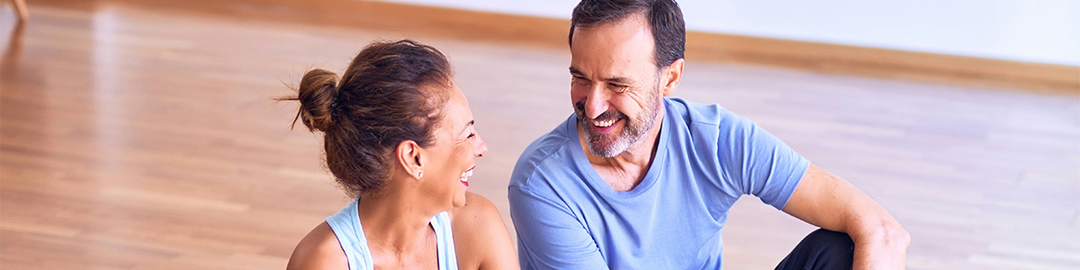 A smiling man and woman sitting on the floor, representing healthy and active lifestyles in Southwest Wyoming